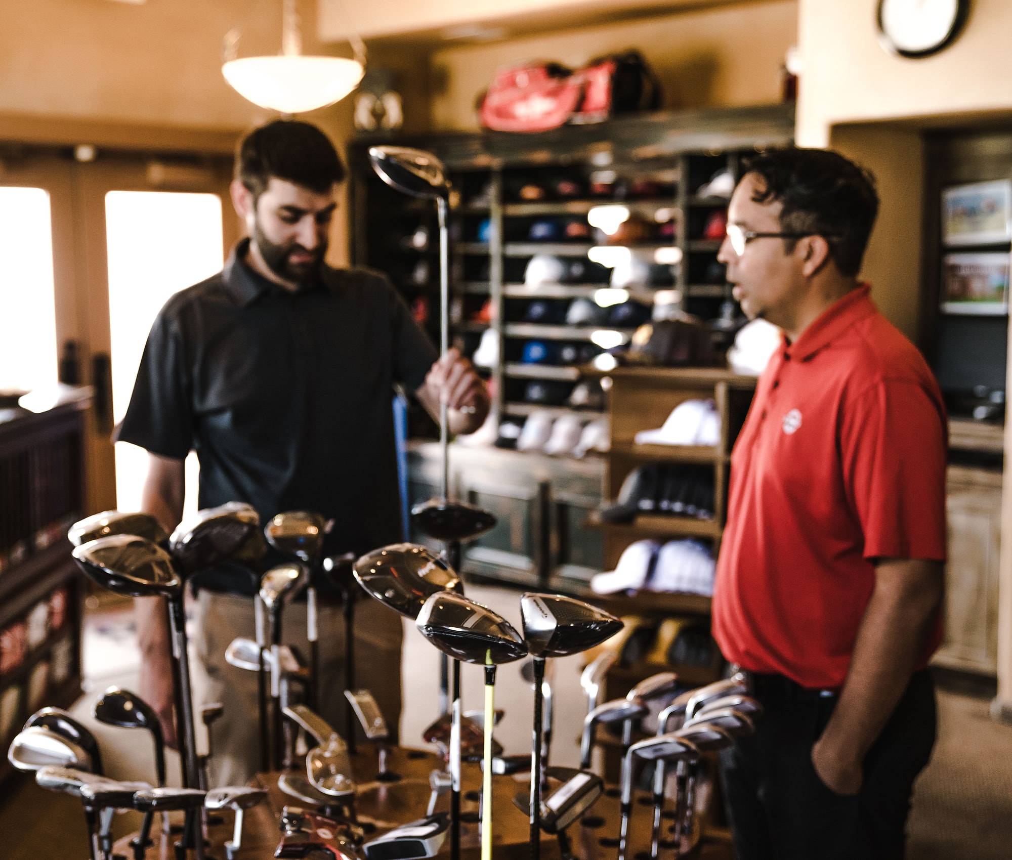 Two golfers examining clubs on a rack in the shop