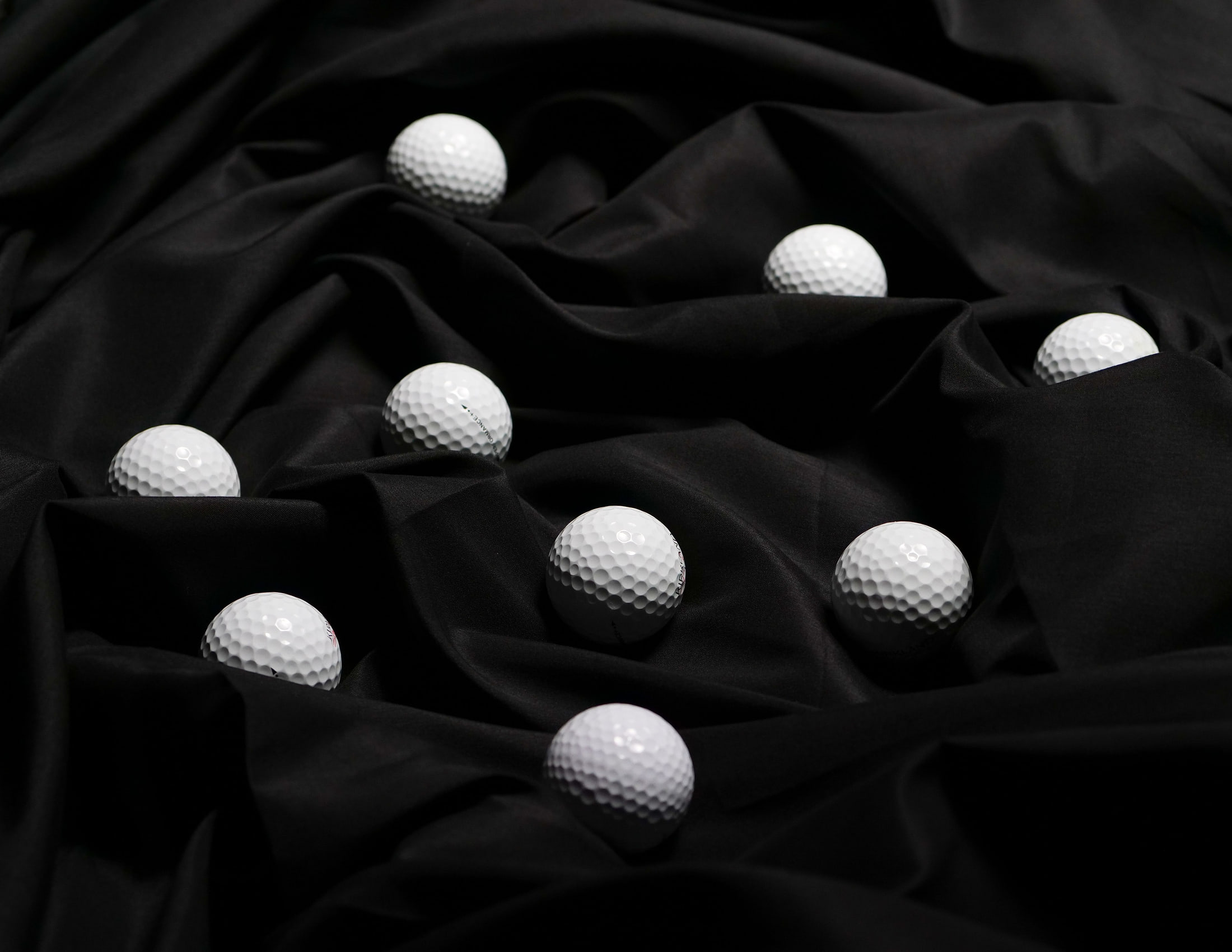 Nine golf balls set out on black studio cloth