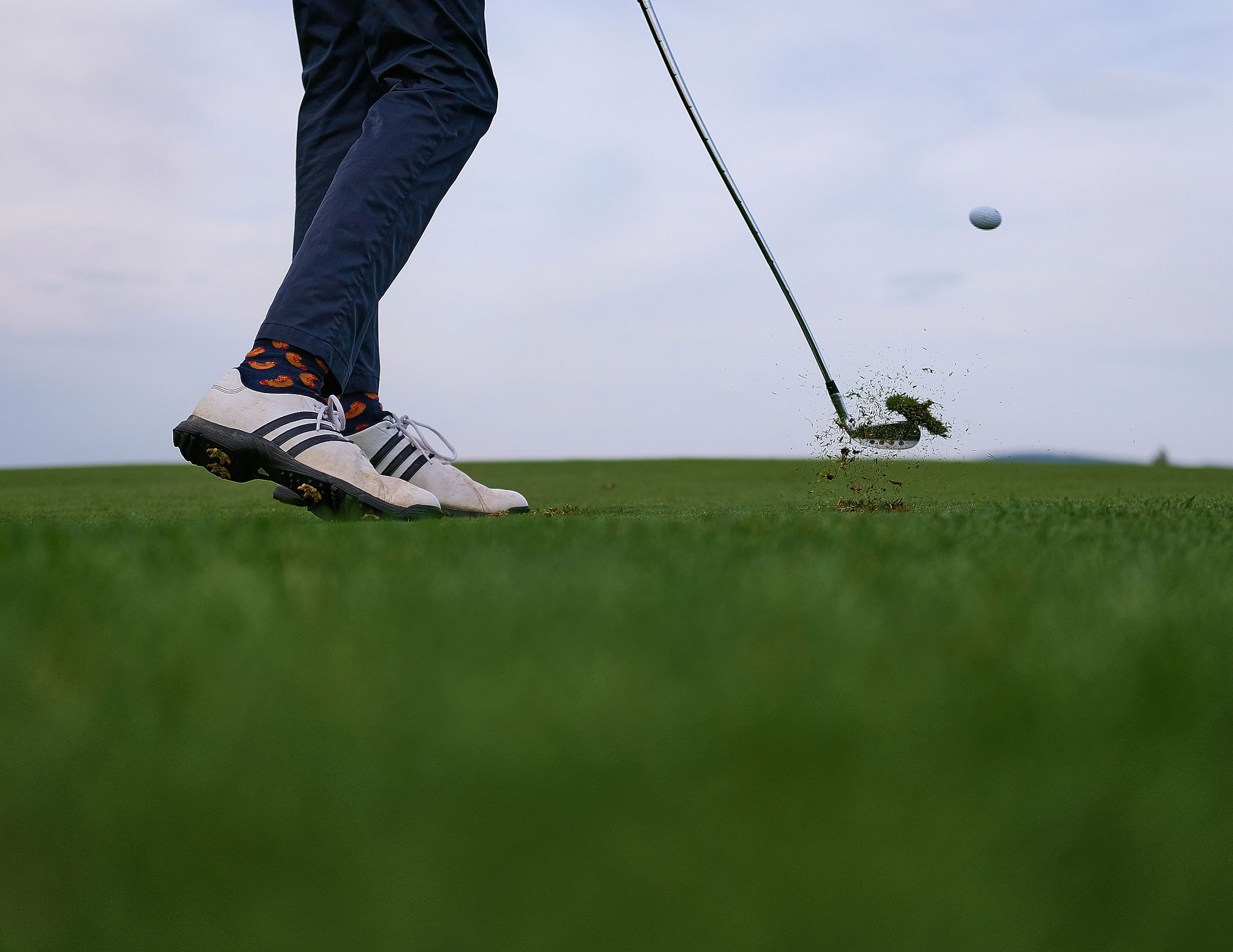 A wedge shot at impact, turf in the air and the ball climbing