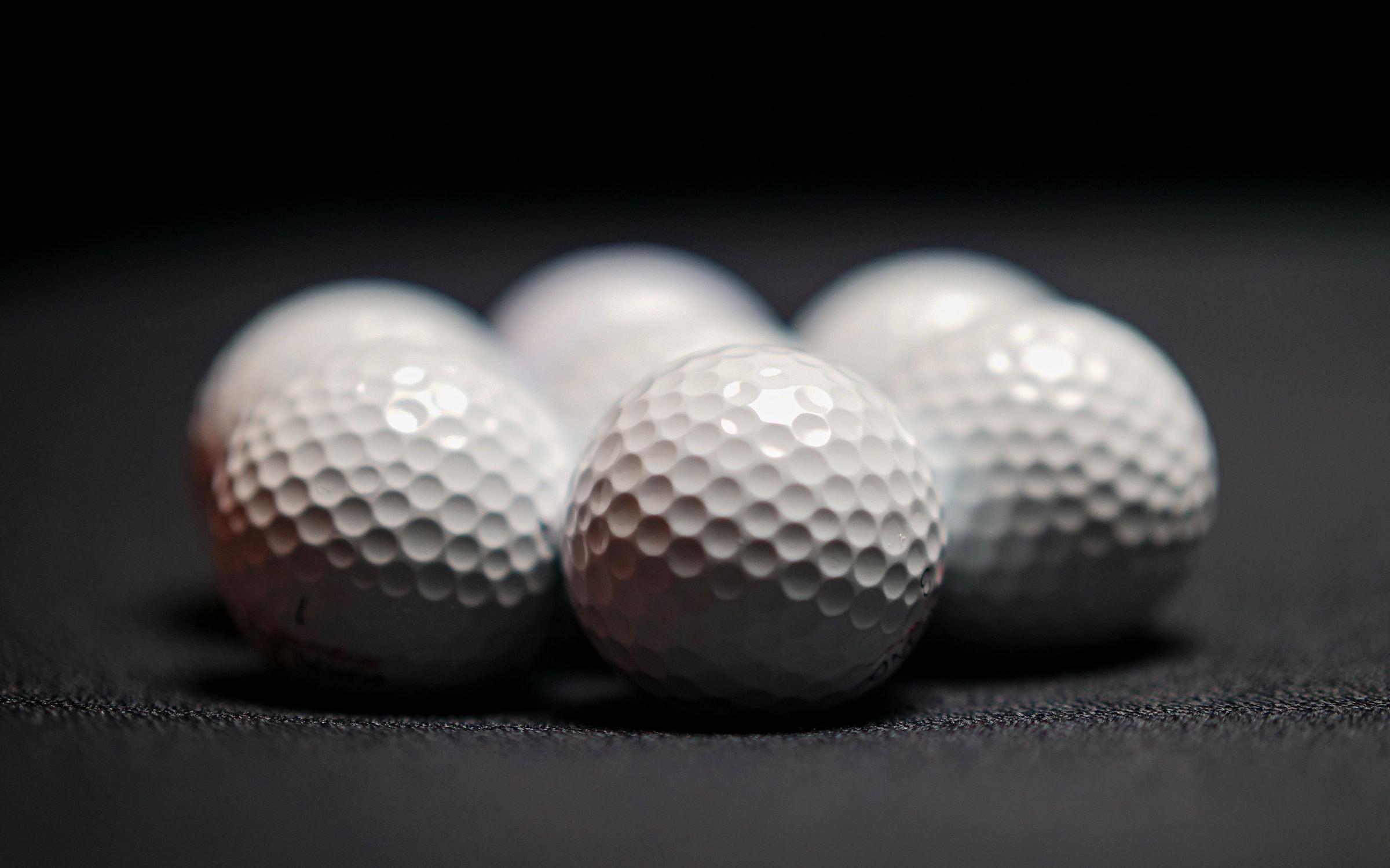 Tour golf balls lit against a dark background
