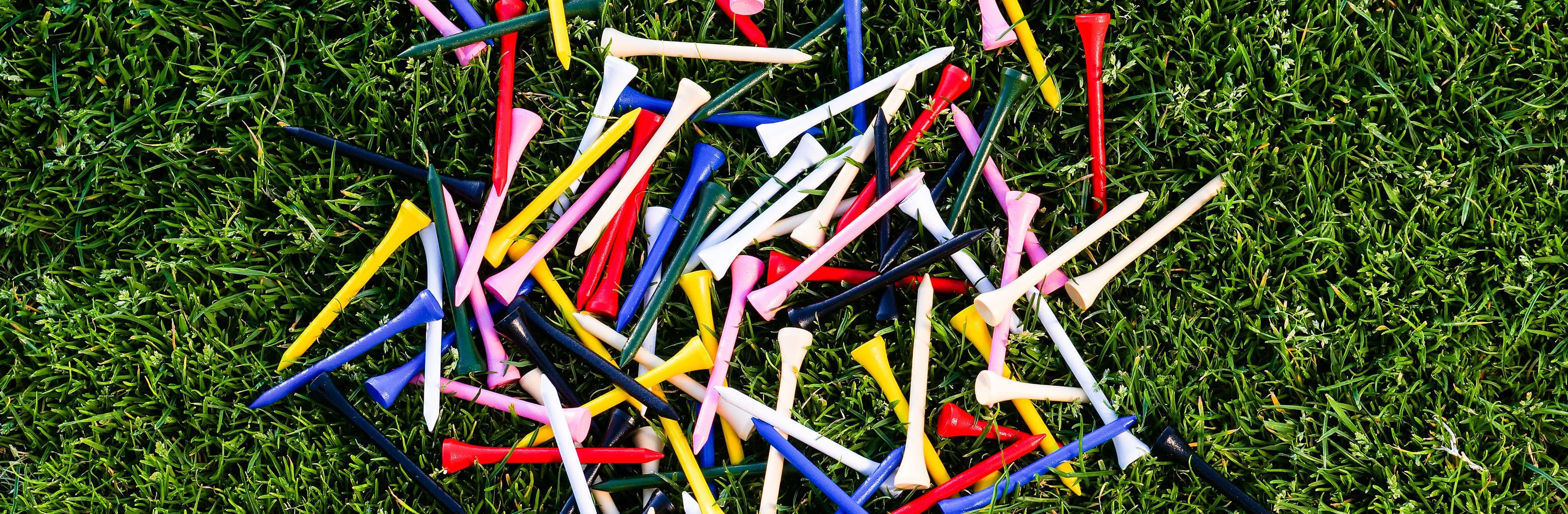 A scattered handful of wooden tees lying on cut grass