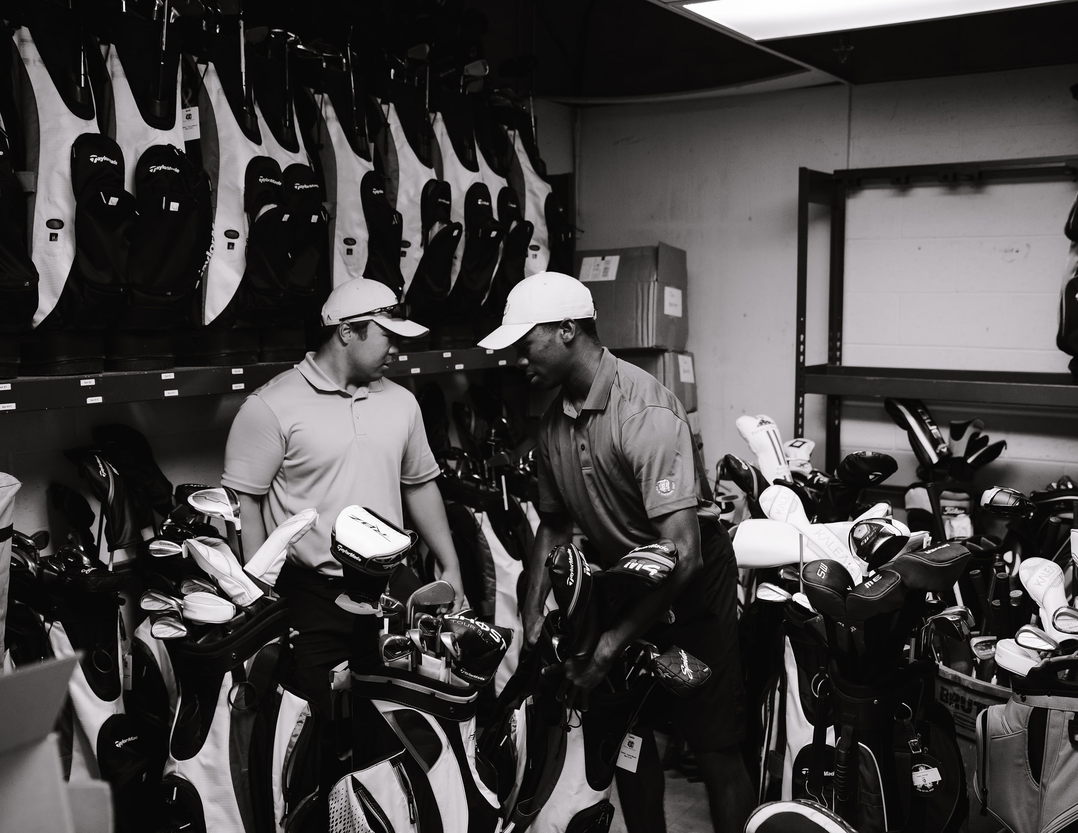 Two members of staff working among racked bags in the back room, in black and white