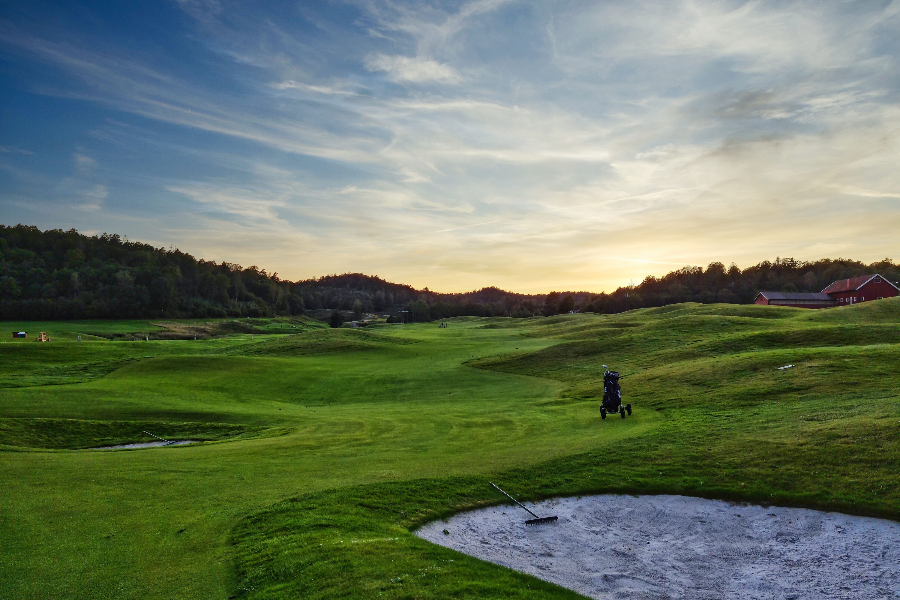A links fairway in the last of the evening light, a trolley standing alone by a bunker