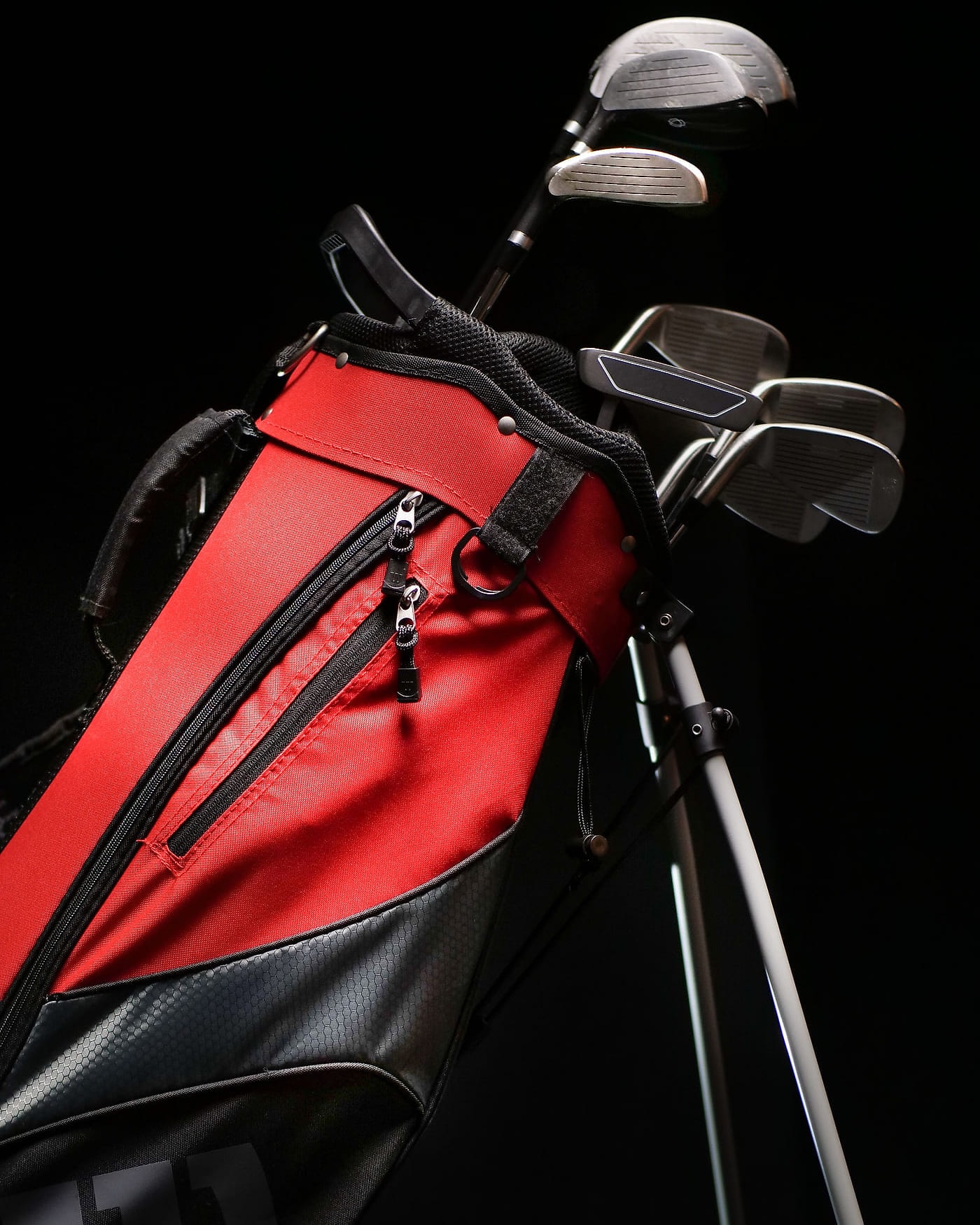 A red stand bag with its legs out, clubs sorted in the top