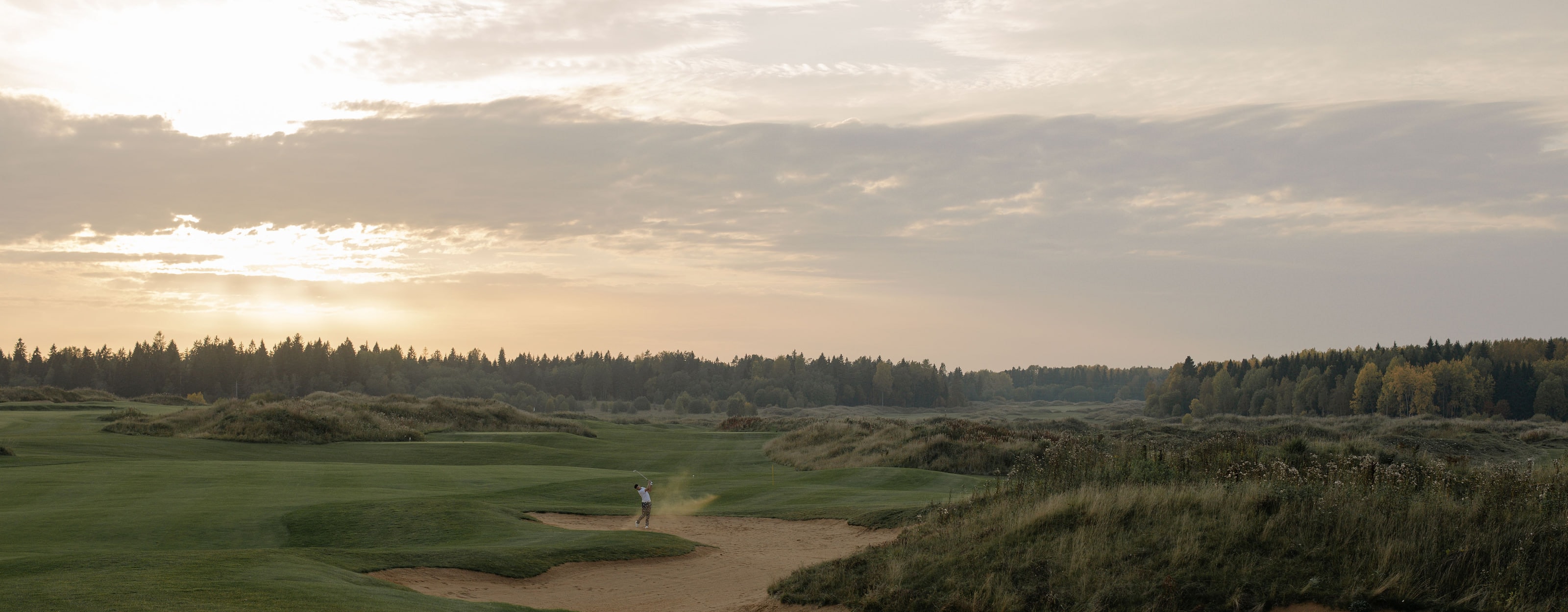 A links course at dusk, a single figure on the fairway