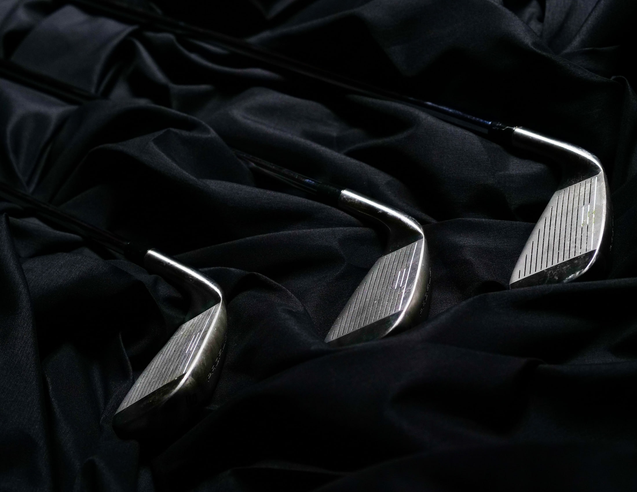Three iron heads laid out on black studio cloth