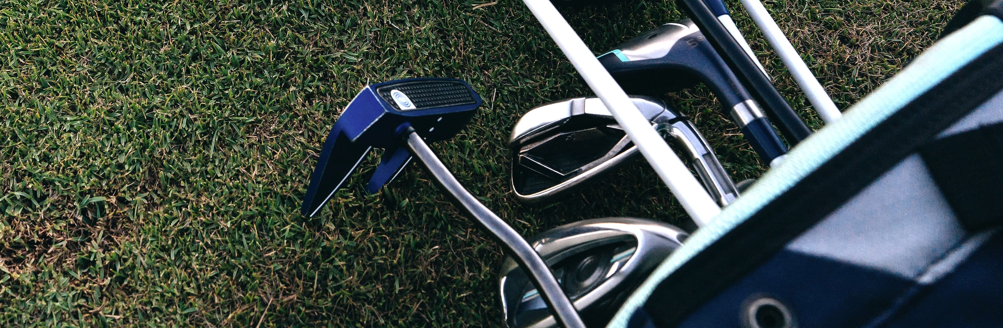 A driver, irons, a wedge and a putter laid out on cut grass