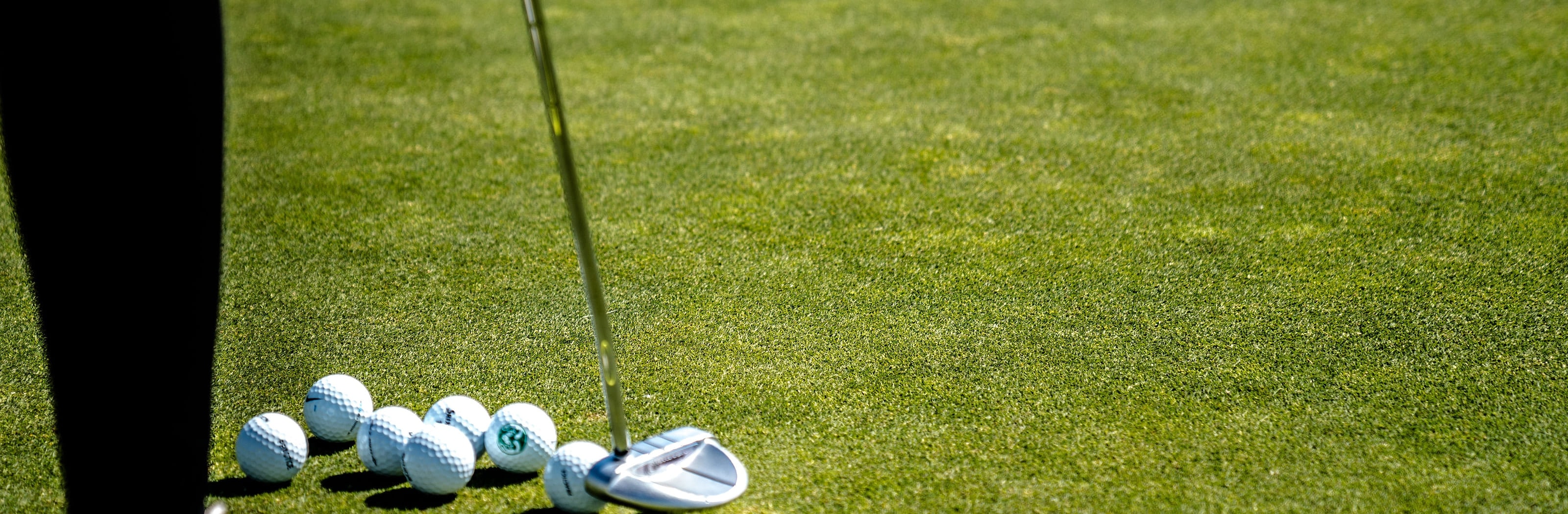 A fairway wood head and three balls lying on cut grass