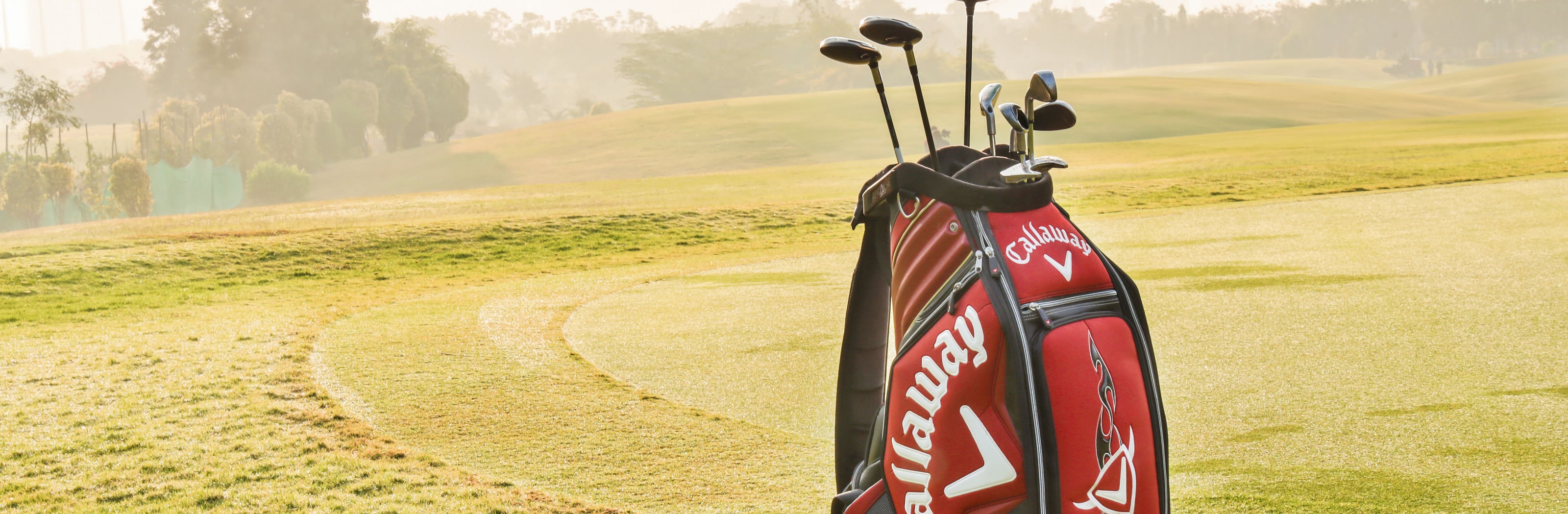 A bag standing alone on an empty fairway in morning haze