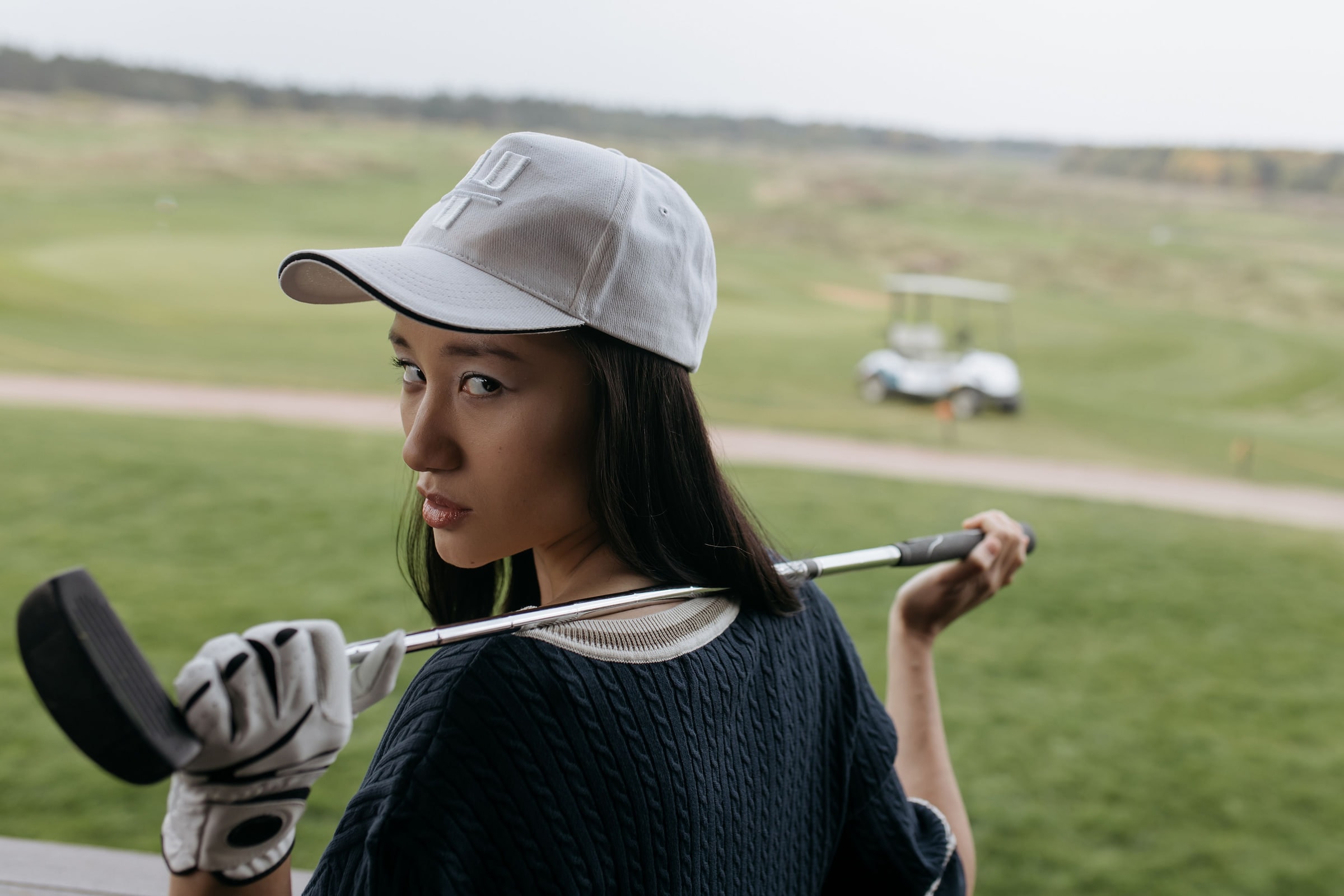 A golfer in a cap with a club over the shoulder, looking back