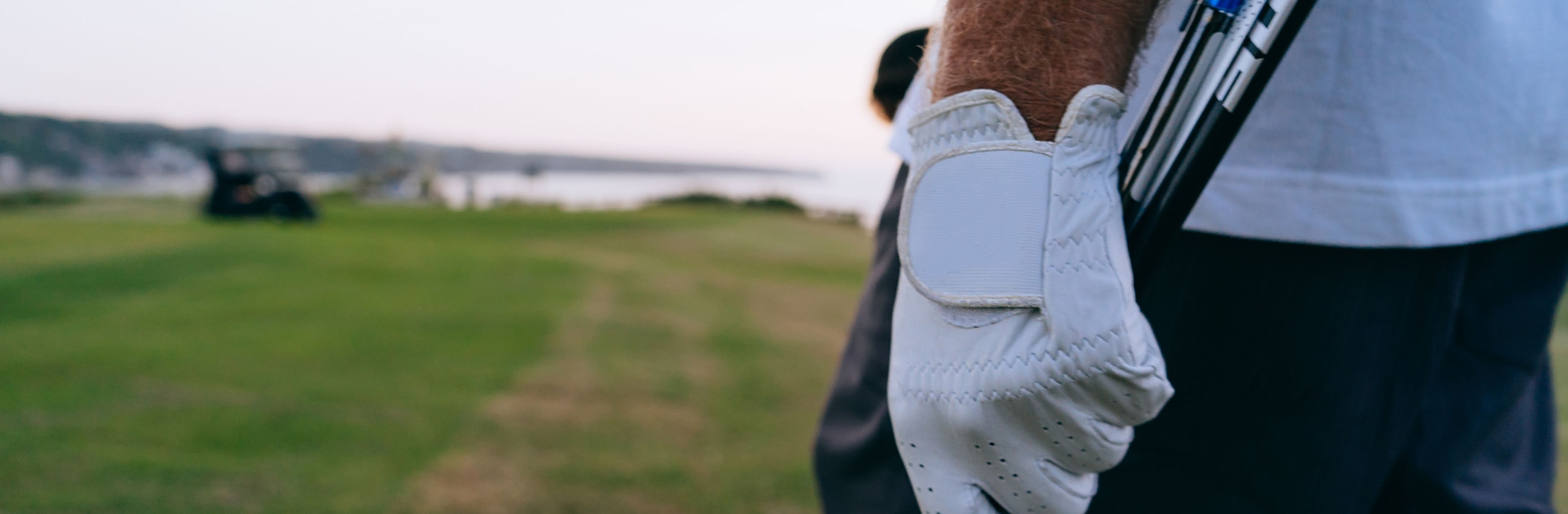 A gloved hand holding clubs over a shoulder on the walk in