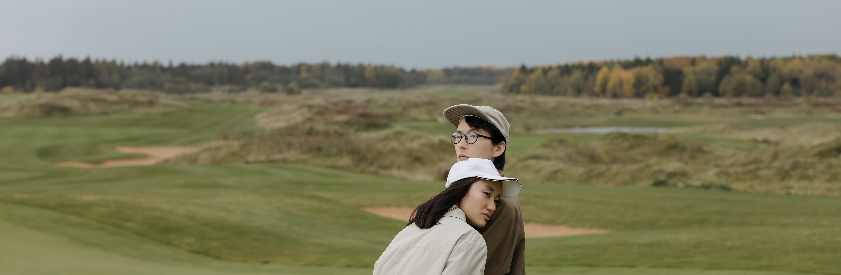 Two golfers standing out on an open links in autumn light