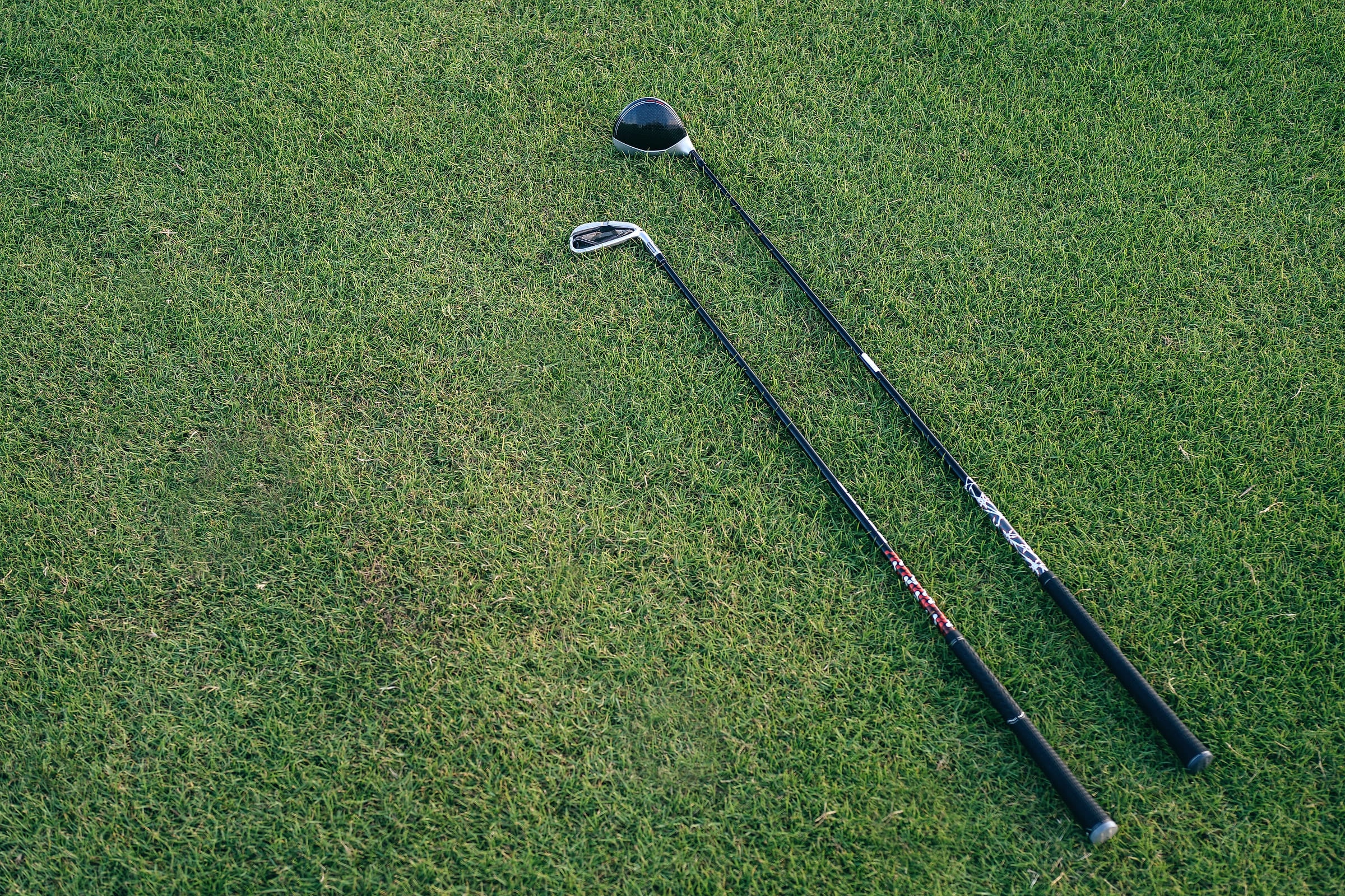 Two clubs lying together on cut grass