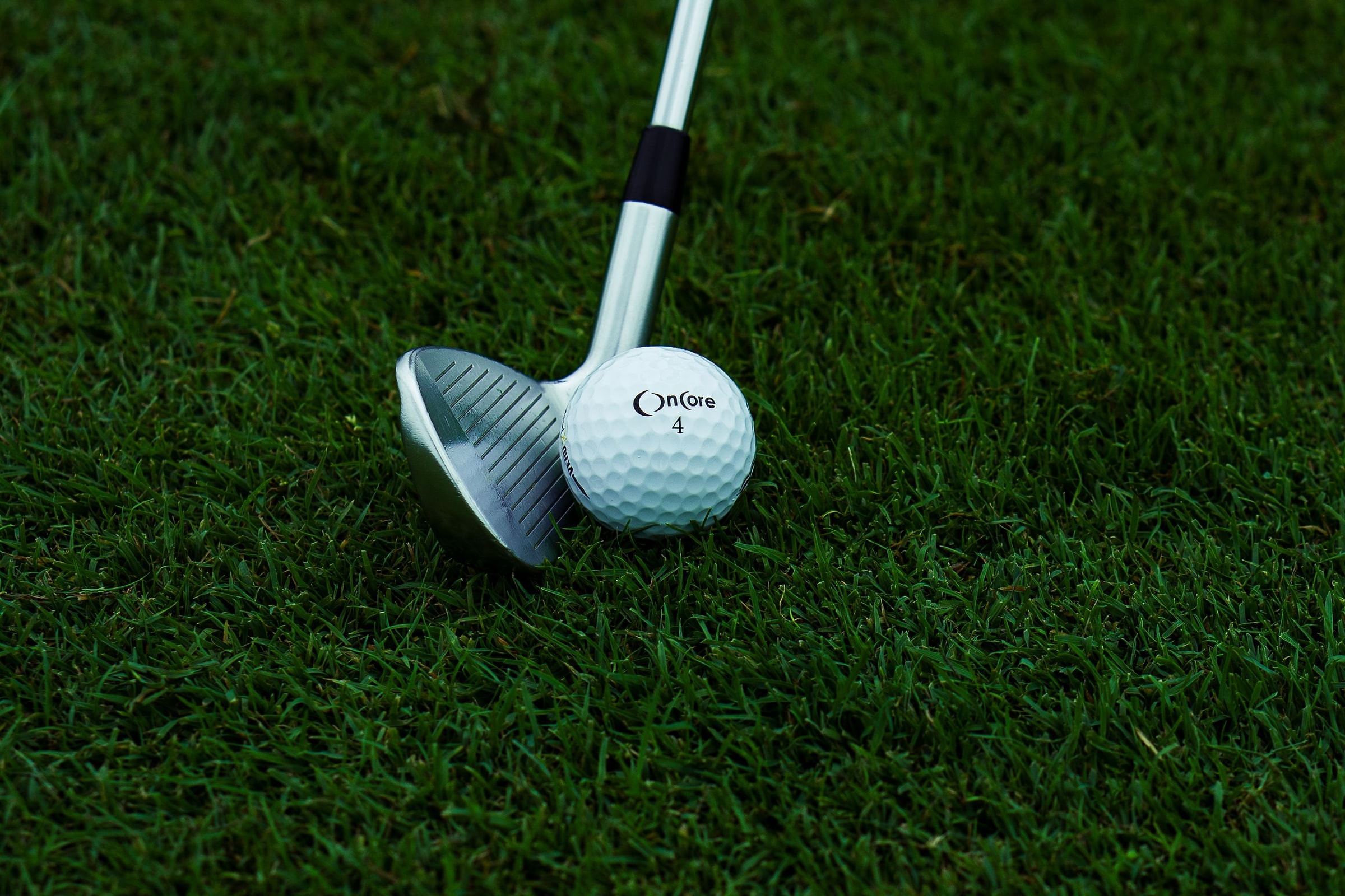 A wedge set behind a ball on close cut grass