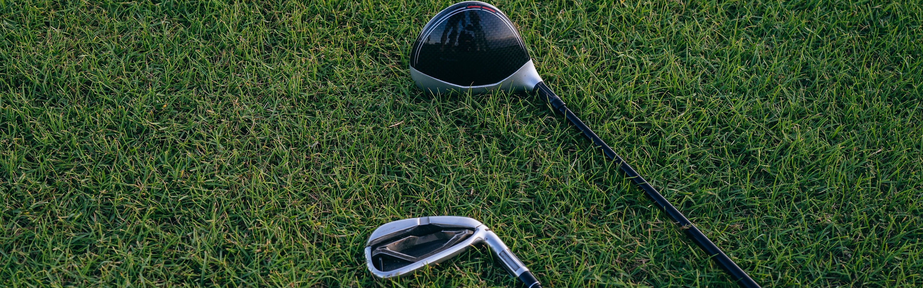 A driver and an iron lying on cut fairway grass