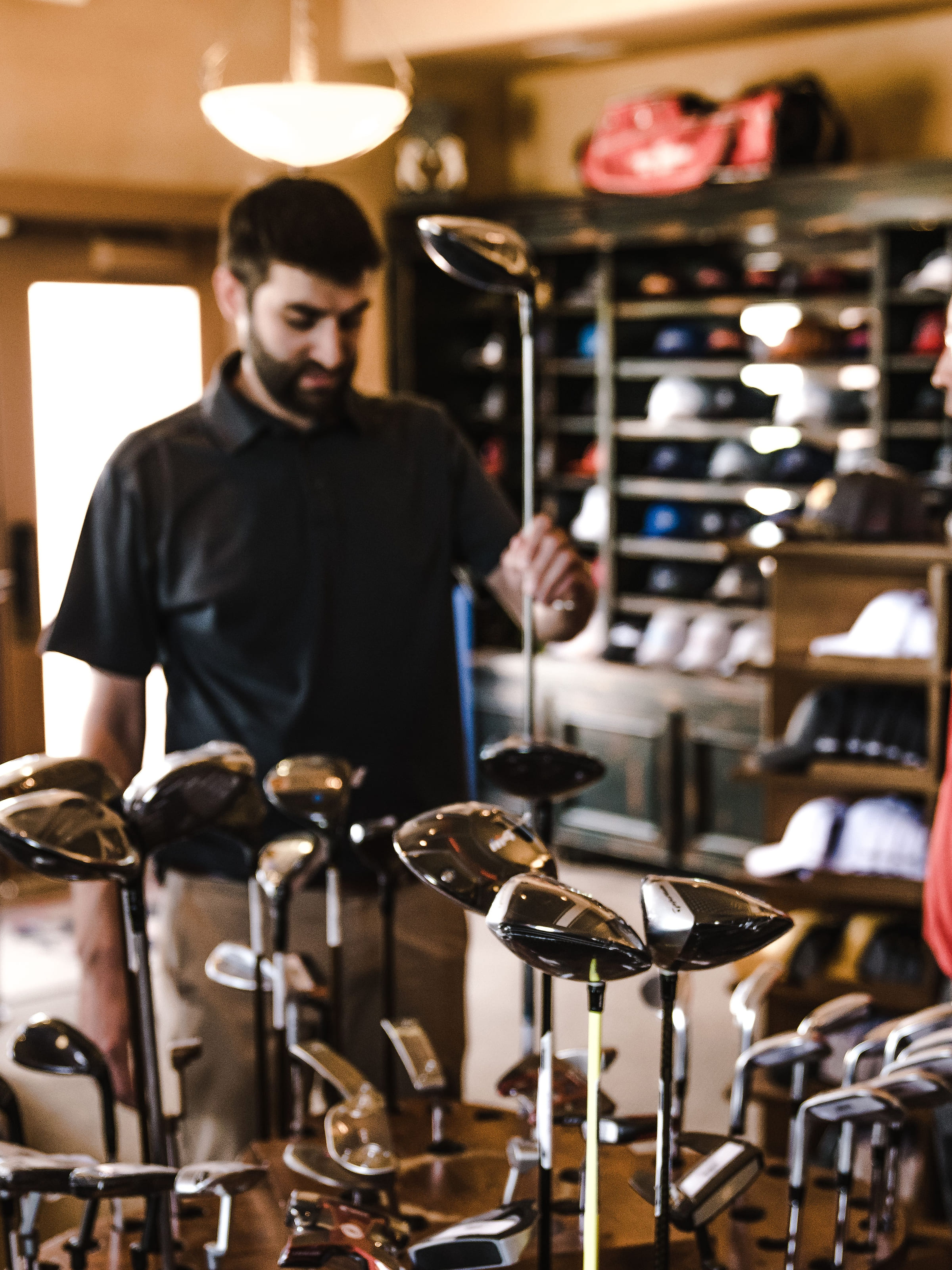 A member of staff at the driver rack in the shop, under the pendant light